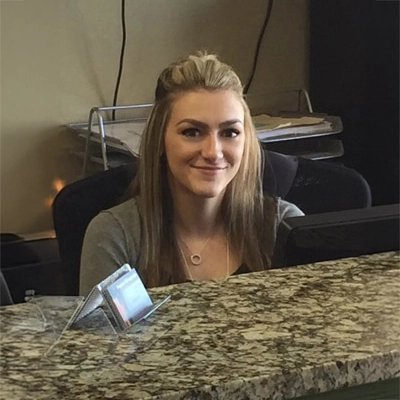 Lauren smiling while sitting behind the front desk.