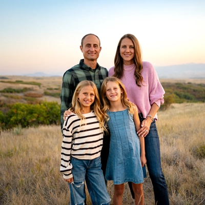 Nick Caras smiling outside with his wife and two daughters.